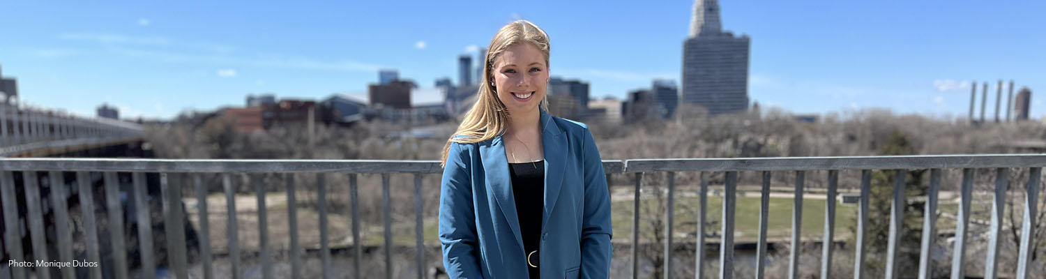 Paige Meyer stands on the East Bank Campus of the U of M with the city skyline behind her