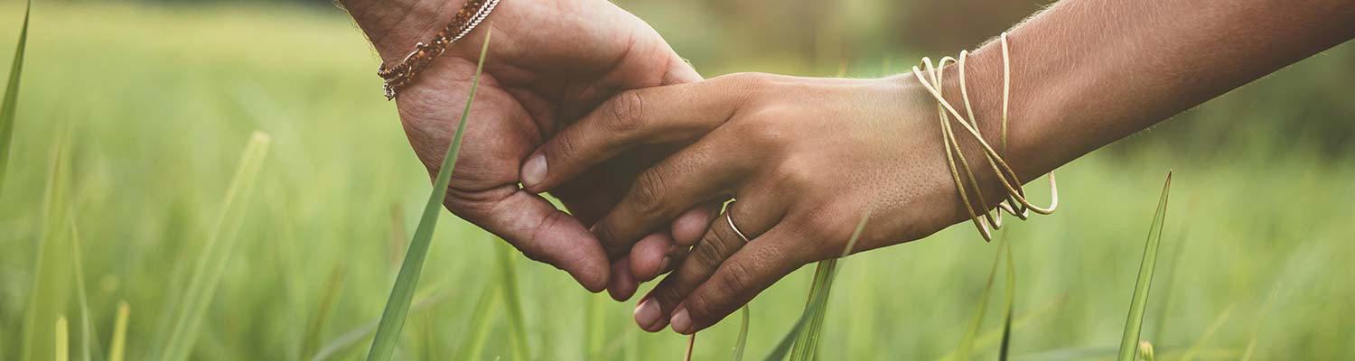 Two hands holding in a field, Human Sexuality header