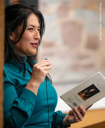 US Poet Laureate Ada Limón holds a microphone and reads from her book