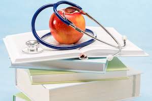 Apple and stethoscope on top of a stack of books