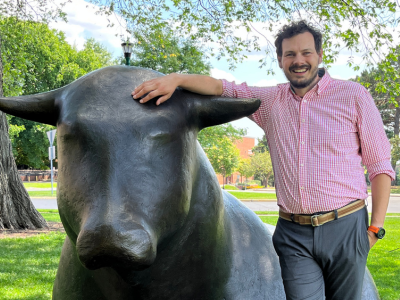 Ben Bowman leaning against one of the bull statues on the St. Paul campus of the U of M