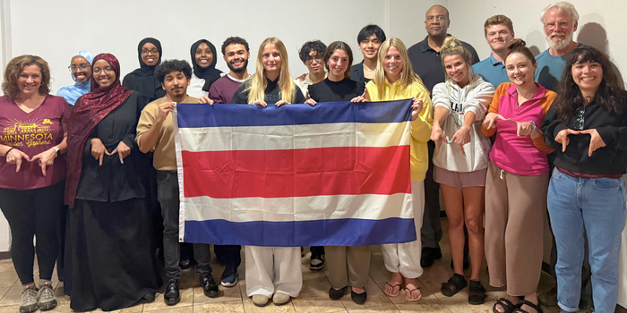 Pura Vida students and faculty hold the Costa Rican flag and make "M"s with their hands