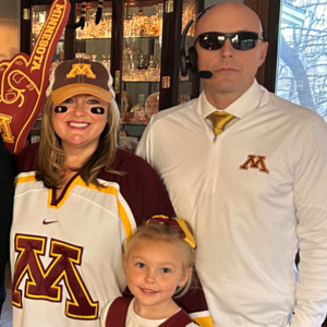 Chris Kispert and his wife and daughter appear in maroon and gold Gopher gear