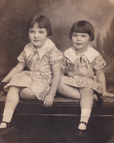 A sepia toned photo of two young girls from the 1940s