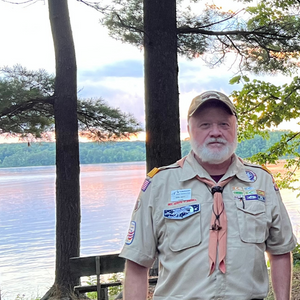 Eric Neff in his Eagle Scout uniform stands in front of a lake at sunset
