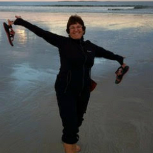 Portrait of Deb Fineman frolicking on a beach.