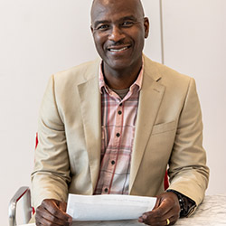 Garfiel Bowen sitting, facing the camera, holding a sheet of paper