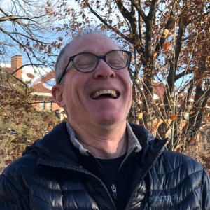 Hugh Pruitt with bare trees in background, laughing