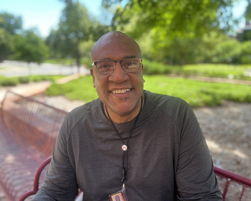 ITI Faculty Director Colin Miller, a bald Black man wearing a grey shirt and glasses, seen from the chest up and smiling