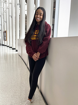 Soliana Ghidewon stands with hands clasped in front wearing a maroon and gold U of M hoodie and black leggings