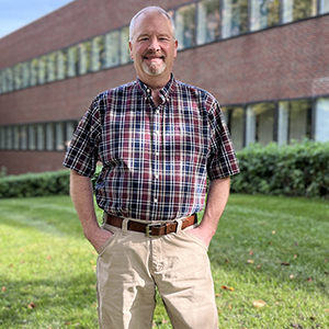 John Raabe stands on the lawn in front of McGrath Library, St. Paul campus