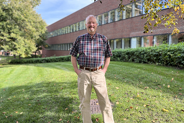 John Raabe stands on the lawn in front of McGrath Library, St. Paul campus