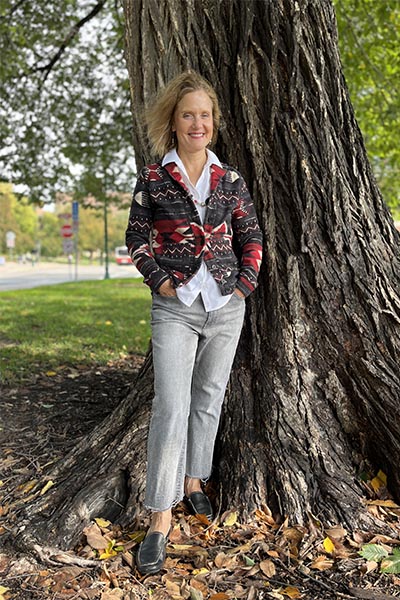 Beth Lory leans against the trunk of large tree
