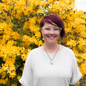 Jessica Stortenbecker stands in front of an azalea bush with yellow blossoms