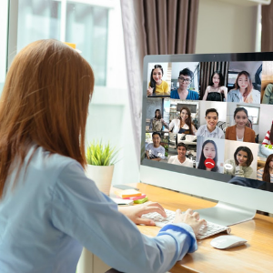 A red-headed woman talks to her remote team via video chat