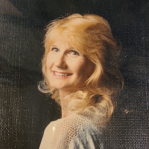 A portrait-like photo of Leslie Bentley, a young woman with blond hair and a light blue top 