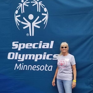 Leslie Bentley stands in front of a large blue Special Olympics banner