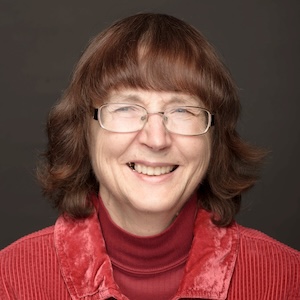 Lois Kennis wears glasses and a red collared shirt over a red turtleneck