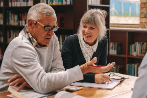 Two older adults hold a conversation in a library.