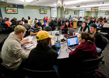 A classroom full of students at round tables