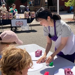 Su Ryeon Kang at a block party helping children with a craft