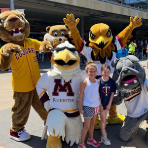 Five UMN system mascots gather with two young fans at Target Field