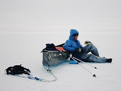 Will Steger eaning on his aluminum canoe, resting on the ice