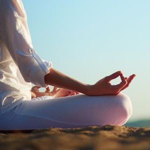Image of woman in lotus position on a beach