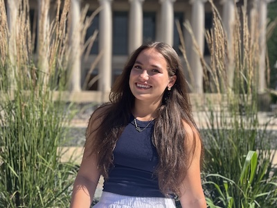 Alex Rapp sitting on a low wall in front of Northrop Auditorium