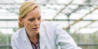 Scientist wearing a lab coat in a greenhouse