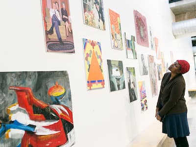 A person looks at a wall of paintings