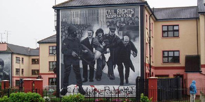 A mural on the side of a house, depicting police and protesters on Bloody Sunday.