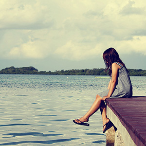  a youth sitting alone at the edge of a dock