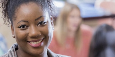 A Black woman stands infront of a seated group