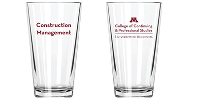 Two clear pint glasses with the CCAPS wordmark on one side and "Construction Management" on the other