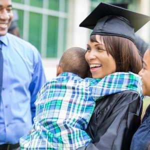 Woman in graduation cap hugs her child
