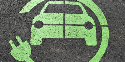 Green painted sign on pavement indicating a car-charging spot
