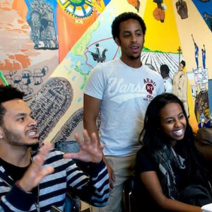 Students talking and laughing before a colorful wall mural