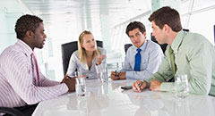 Four people in boardroom talking
