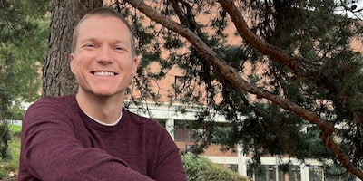 Joe Krohn sits on the steps behind Ruttan Hall