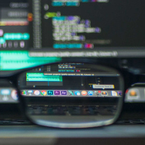 image of blurry computer monitors coming into focus behind a pair of glasses