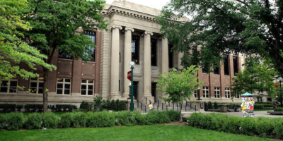 An exterior photo of Walter Library surrounded by lush green grass and trees