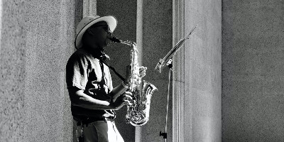 A jazz musician plays saxophone in a wide cloistered structure