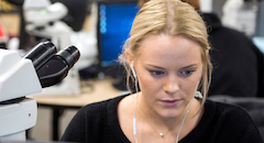 Female student with microscope and headphones 