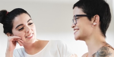 Two people smiling and talking in a bright room