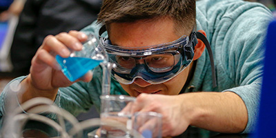 Student with goggles on performing experiment