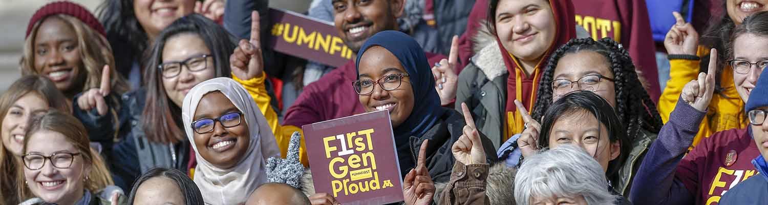 A group of diverse students holding "First Gen" and "#UMN First" signs. showing pride in being first generation college students