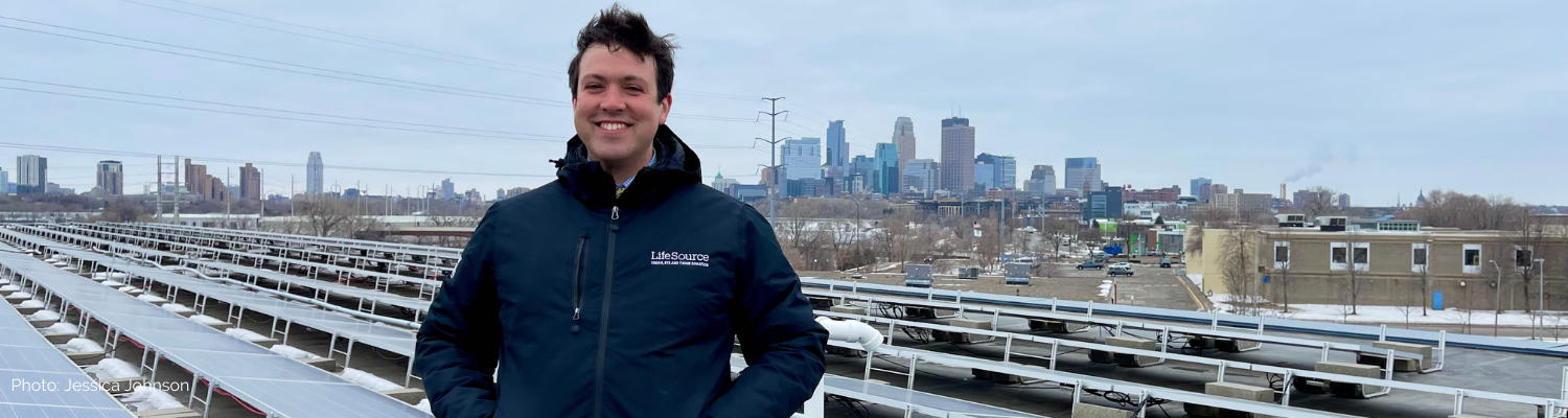 Daniel Samuelson-Roberts stands on a rooftop with the Minneapolis skyline in background