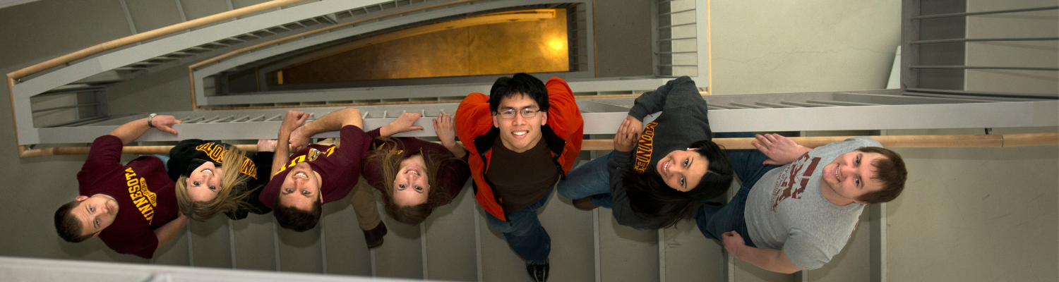 group of U of M students look up a stairwell at the camera