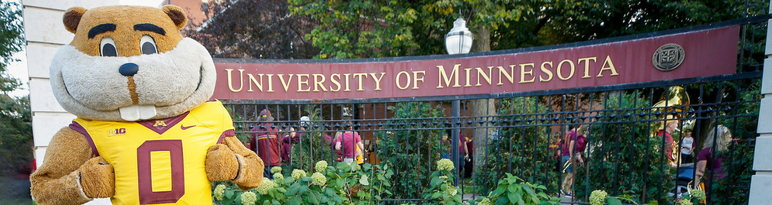 Goldy Gopher stands proudly in front of a Twin Cities campus sign that reads University of Minnesota